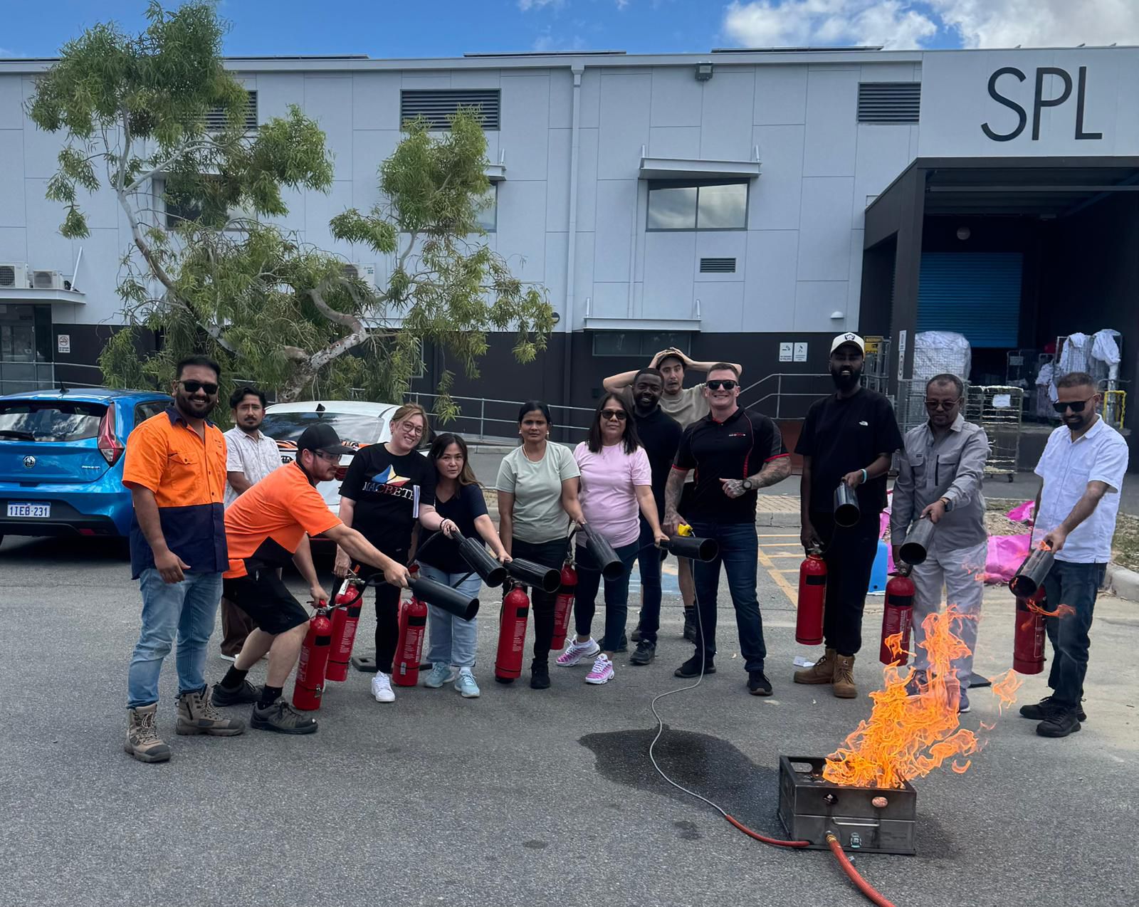 Group fire extinguisher training with participants holding extinguishers around live fire
